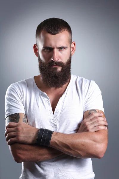 Portrait of handsome bearded man standing with crossed arms, isolated on grey background — Stock Photo, Image