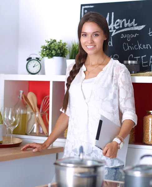 Молодая женщина использует планшетный компьютер, чтобы готовить на кухне — стоковое фото