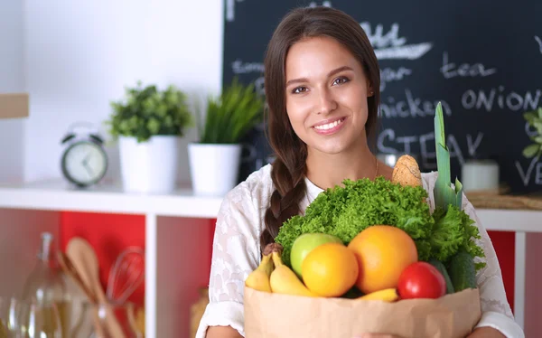 Ung kvinna som håller i matkassen med grönsaker — Stockfoto