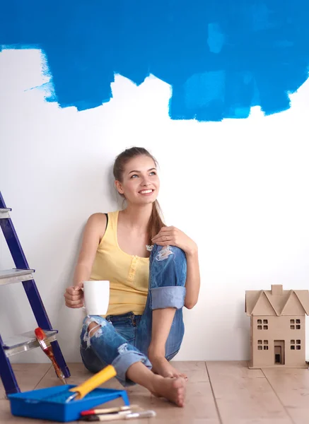 Portret van vrouwelijke schilder zittend op de vloer in de buurt van muur naar schilderij. — Stockfoto