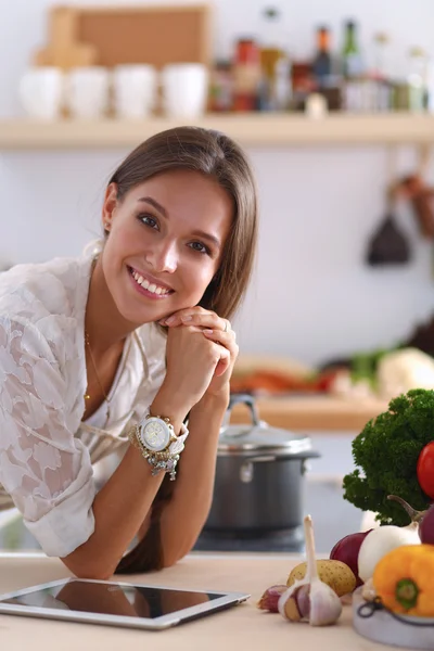 Young woman using a tablet computer to cook in her kitchen — Stock Photo, Image