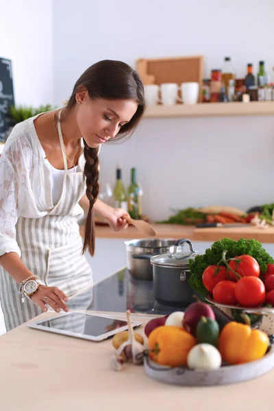 Junge Frau kocht mit Tablet-Computer in ihrer Küche — Stockfoto