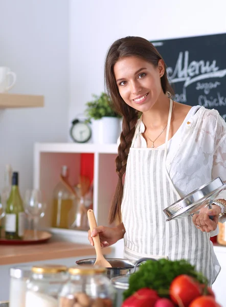 Mutfakta ahşap kaşıkla yemek pişiren kadın