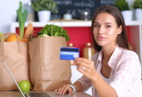 Smiling woman online shopping using tablet and credit card in kitchen — Stock Photo, Image