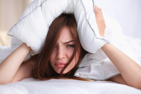 Mujer acostada en la cama y cerrando las orejas con almohada — Foto de Stock