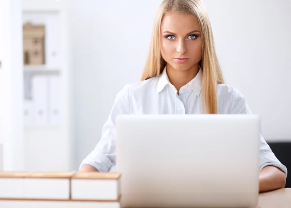 Attractive businesswoman sitting on a desk with laptop in the office — Stock Photo, Image