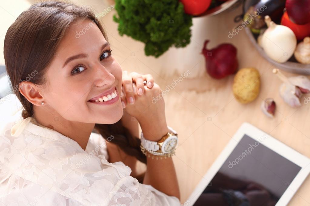 Young woman using a tablet computer to cook in her kitchen