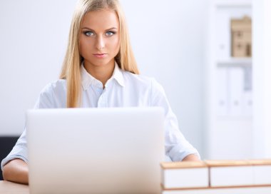 Ofiste dizüstü bilgisayarı olan çekici bir iş kadını.