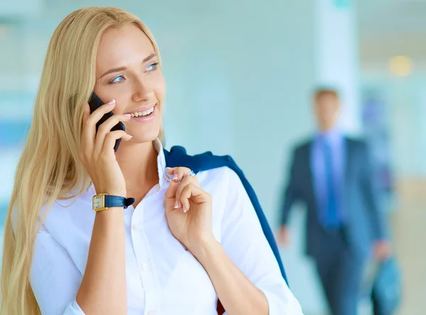 Zakenvrouw staat tegen kantoorraam te praten op mobiele telefoon — Stockfoto