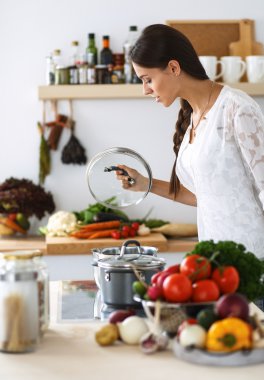 Mutfakta sobanın yanında duran genç bir kadın.