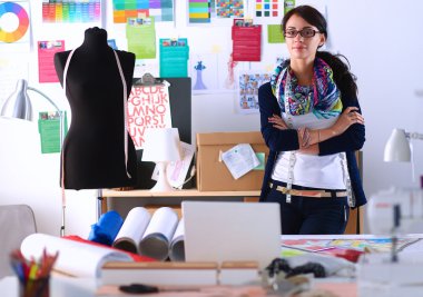 Güzel moda tasarımcısı stüdyoda duruyor.