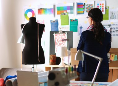 Güzel moda tasarımcısı stüdyoda duruyor.