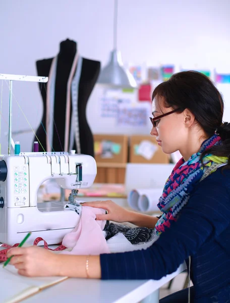 Young woman sewing while sitting at her working place — Stock Photo, Image