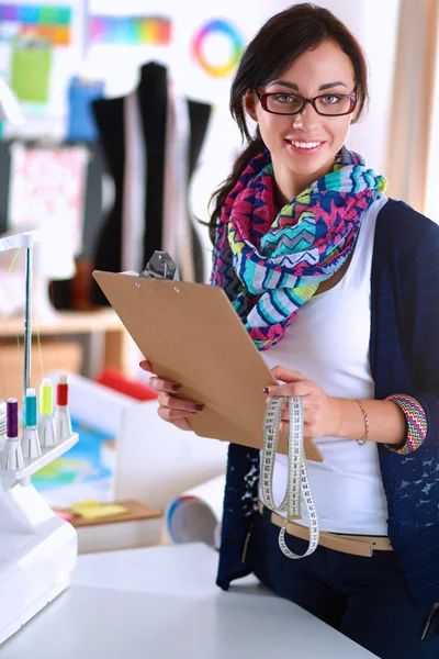 Hermoso diseñador de moda de pie con carpeta en el estudio — Foto de Stock