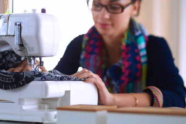 Young woman sewing while sitting at her working place — Stock Photo, Image