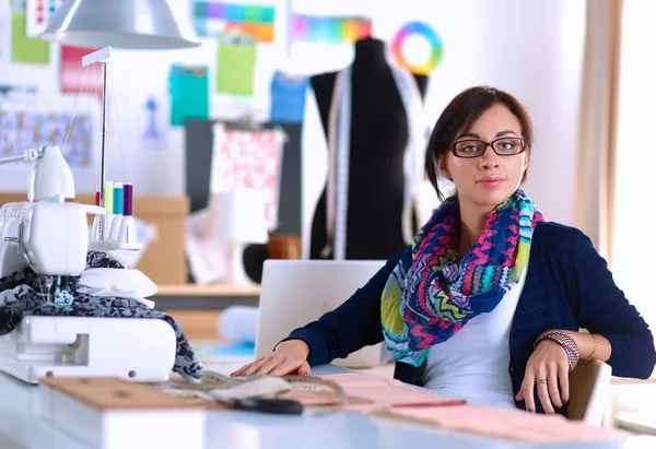 Schöne Modedesignerin sitzt am Schreibtisch im Atelier — Stockfoto