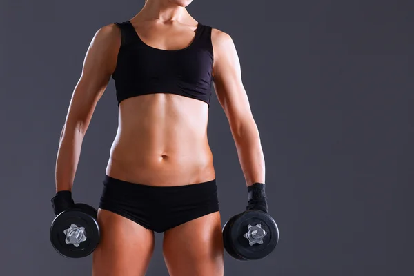 Atletisk kvinna som pumpar upp muskler med hantlar — Stockfoto