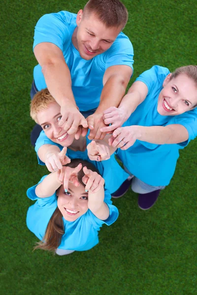 Group of young people standing on green grass pointing up — Stock Photo, Image
