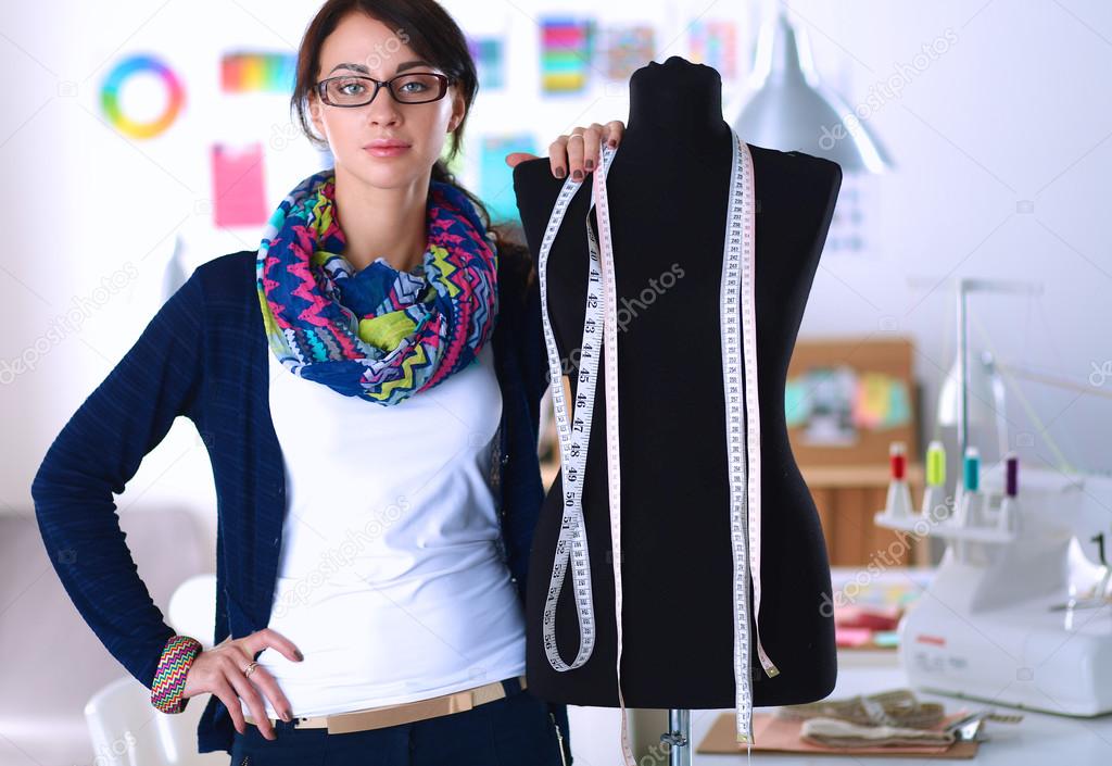 Smiling fashion designer standing near mannequin in office