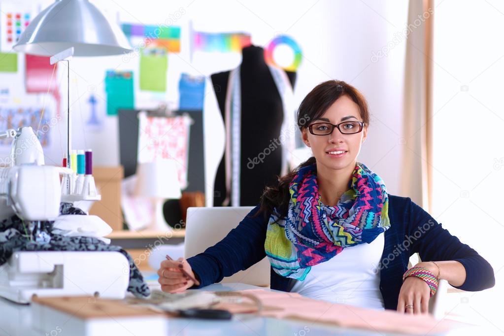 Beautiful fashion designer sitting at the desk in studio