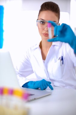 Kadın araştırmacı, beyaz arka planda izole edilmiş ilaç şişeleri ve mataralarla çevrili.