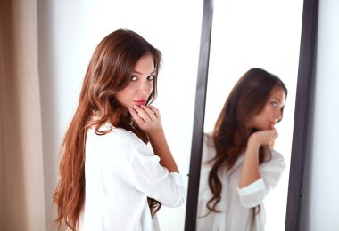 Genç kadın kendini evde aynada yansıma arıyor