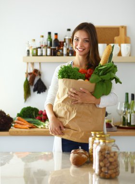 Elinde sebzeli alışveriş torbası tutan genç bir kadın.
