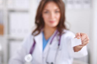 Güzel, genç, gülümseyen bayan doktor masada oturuyor ve yazıyor..