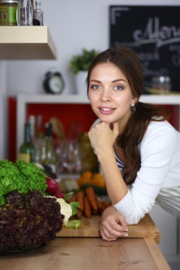 Genç bir kadın mutfakta duruyor.