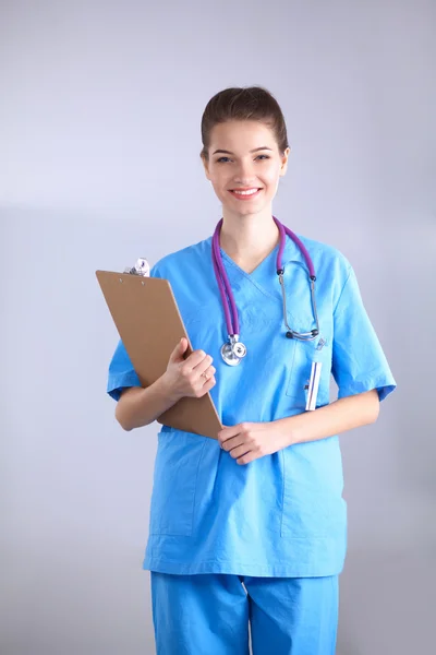 Médico sonriente con una carpeta en uniforme de pie en el hospital — Foto de Stock