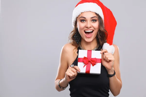 Donna in cappello Babbo Natale in possesso di doni, isolato su grigio — Foto Stock