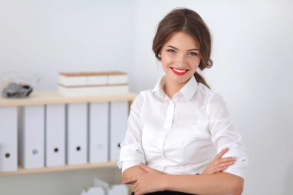 Atrakcyjna bizneswoman stojąca przy ścianie w biurze — Zdjęcie stockowe