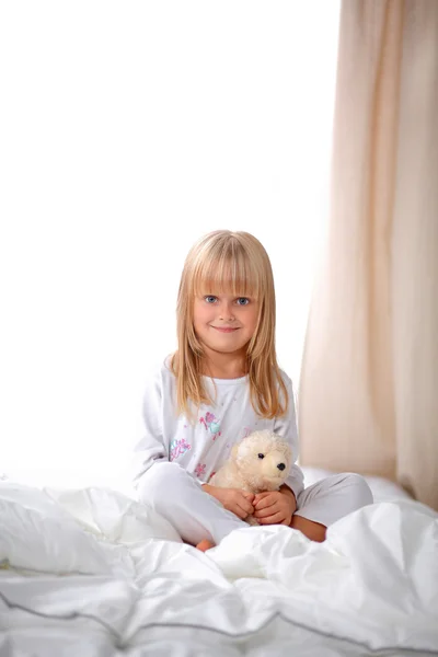 Liten flicka med Nalle ligger på sängen hemma — Stockfoto