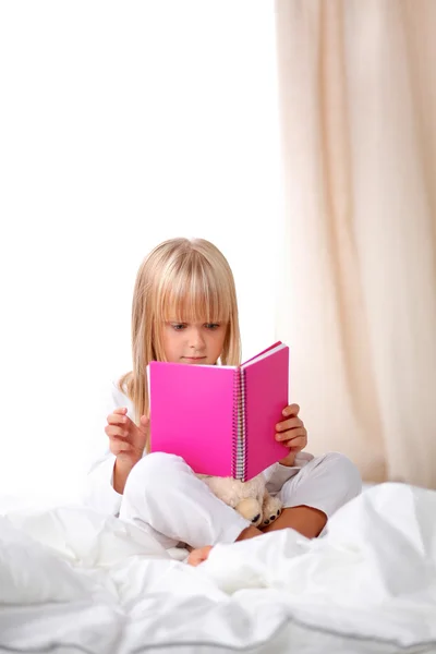 Petite fille couchée au lit et lisant un livre — Photo