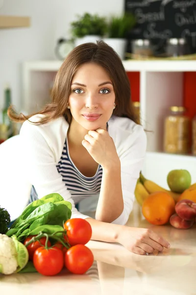 Jonge vrouw zit in de buurt van bureau in de keuken — Stockfoto