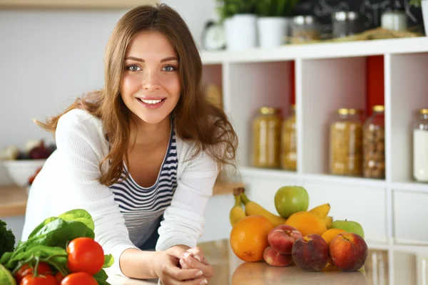 Jonge vrouw zit in de buurt van bureau in de keuken — Stockfoto