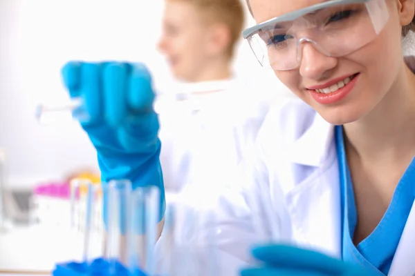 Woman researcher is surrounded by medical vials and flasks, isolated on white background — Stock Photo, Image