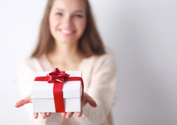 युवा महिला खुश मुस्कान हाथों में उपहार बॉक्स पकड़ती है, ग्रे पृष्ठभूमि पर खड़े — स्टॉक फ़ोटो, इमेज
