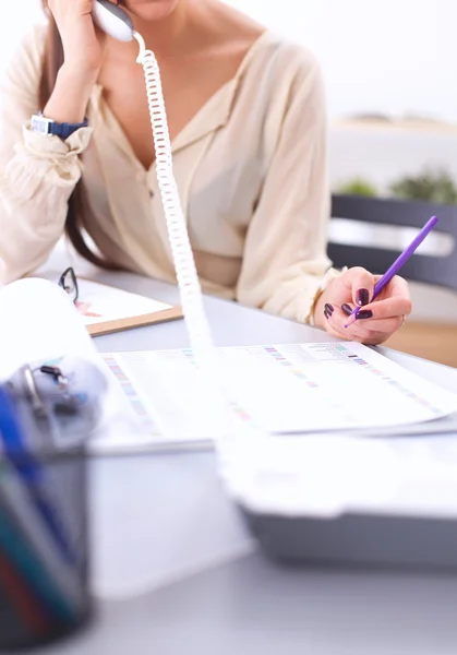 Joven mujer de negocios sentada en el escritorio y hablando por teléfono — Foto de Stock