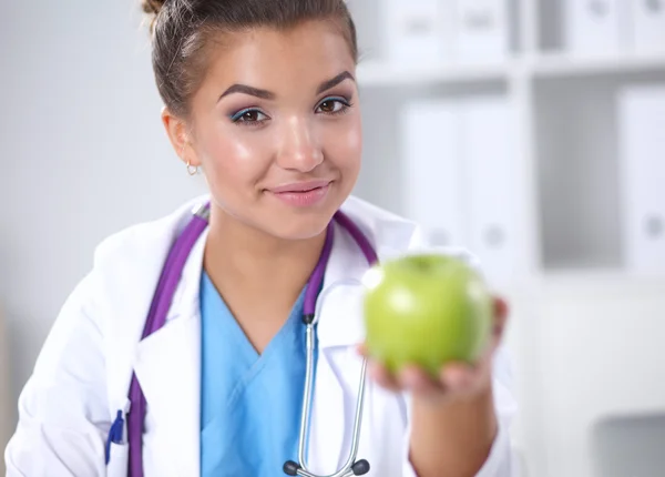 Mão médica feminina segurando uma maçã verde, sentada — Fotografia de Stock