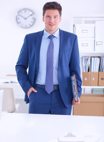 Hombre de negocios o gerente de pie contra su escritorio en la oficina —  Fotos de Stock