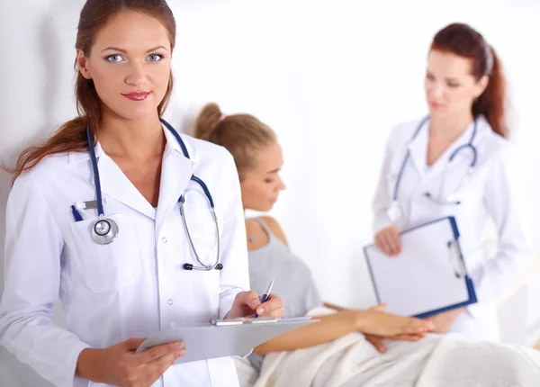 Médico sonriente con una carpeta en uniforme de pie en el hospital — Foto de Stock