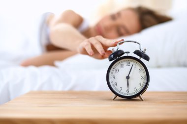 Evdeki yatak odasında uyuyan genç kadın ve çalar saat.