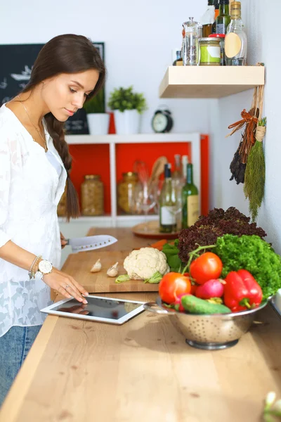 Wanita muda menggunakan komputer tablet untuk memasak di dapurnya — Stok Foto