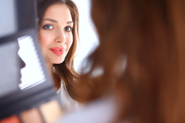 Joven hermosa mujer haciendo maquillaje cerca del espejo —  Fotos de Stock