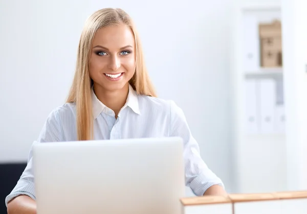 Attraente donna d'affari seduta su una scrivania con computer portatile in ufficio — Foto Stock