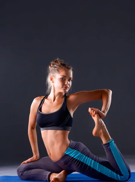 Jonge vrouw doen yoga oefening op grijze achtergrond — Stockfoto