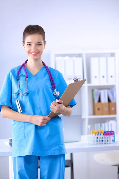 Lächelnde Ärztin mit Ordner in Uniform steht im Krankenhaus — Stockfoto