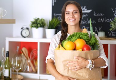 Elinde sebzeli alışveriş torbası tutan genç bir kadın.