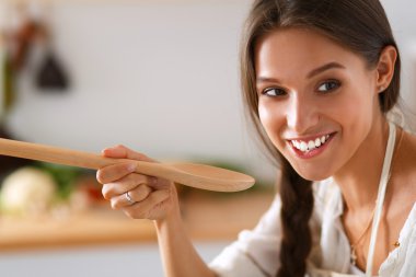 Mutfakta ahşap kaşıkla yemek pişiren kadın